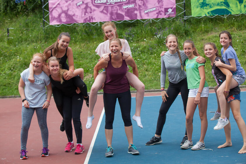 Lachende Kinder nehmen sich huckepack im Feriencamp Salzburg