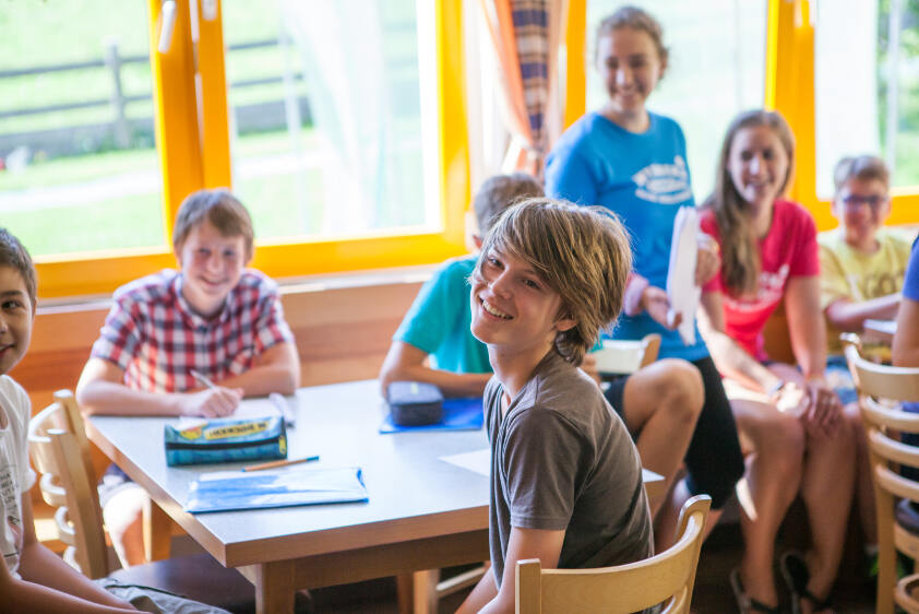 Die Kinder aus der Ferienbetreuung Klagenfurt sitzen gemeinsam am Tisch 