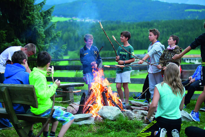 Kinder braten Stockbrot am Lagerfeuer im Abenteuerurlaub Kinder