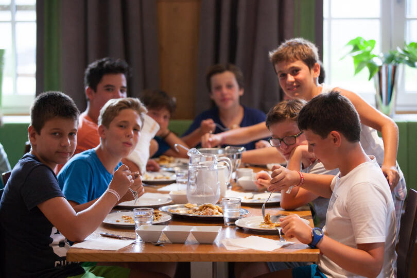Die Teilnehmer der Ferienbetreuung Englisch sitzen am Tisch und essen gemeinsam