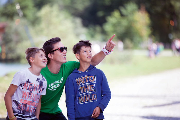 Betreuer zeigt zwei Jungs etwas im Sommercamp Kinder