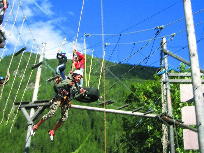 Junge seilt sich ab im Hochseilgarten im Sommercamp Kinder