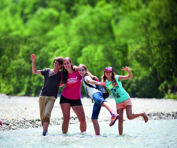 Betreuer und Mädchen stehen im Fluss im Sommercamp Kinder
