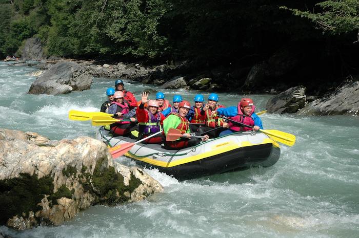 Die Jugendlichen des Actioncamps sitzen in einem Boot beim River Rafting