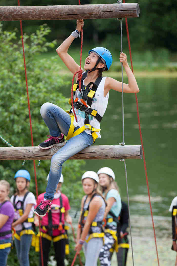 Mädchen klettert auf Ästen im Sommercamp Kinder