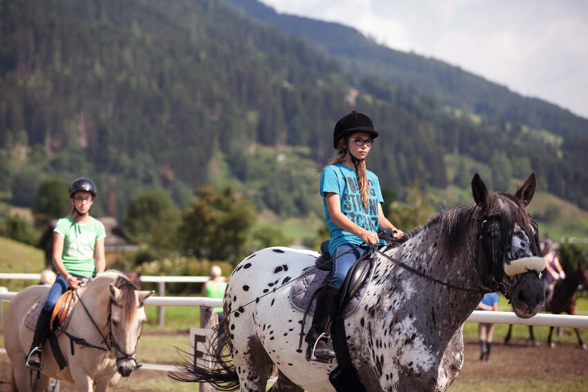 Mädchen reiten auf Reitplatz im Sommercamp Kinder