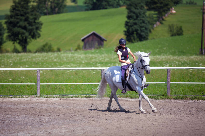 Mädchen reitet auf einem Pferd auf einer Koppel während ihres Reitcamps Österreich