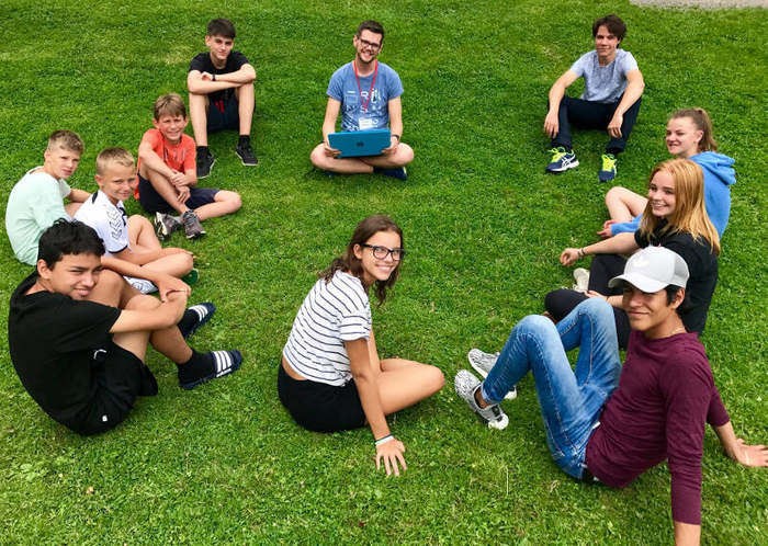 Teilnehmer sitzen auf Wiese im Englisch Feriencamp