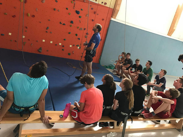 Betreuer erklärt Grundlagen des Kletterns im Englisch Feriencamp