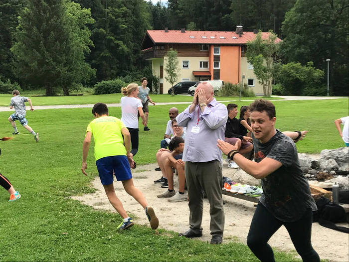 Betreuer spielt mit Jugendlichen verstecken im Englisch Feriencamp