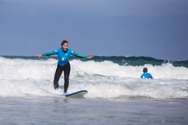 Mädchen steht auf Surfbrett auf der Surffreizeit