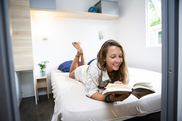 Mädchen liest auf Bett auf der Surffreizeit