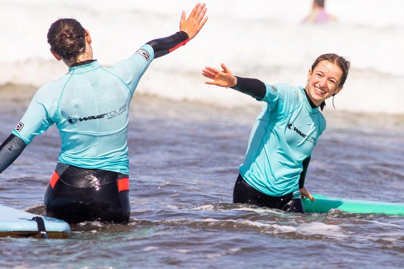 Zwei Mädchen geben sich ein High Five auf der Surffreizeit