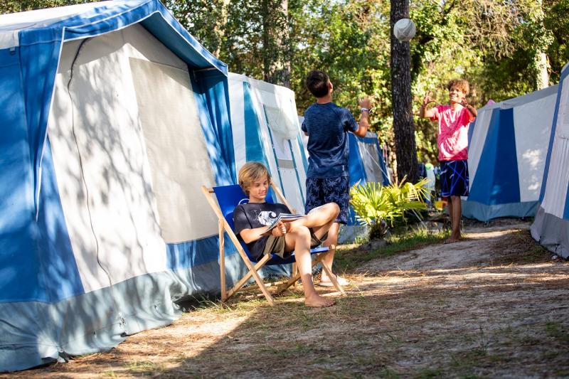 Junge liest vor Zelt auf der Surffreizeit