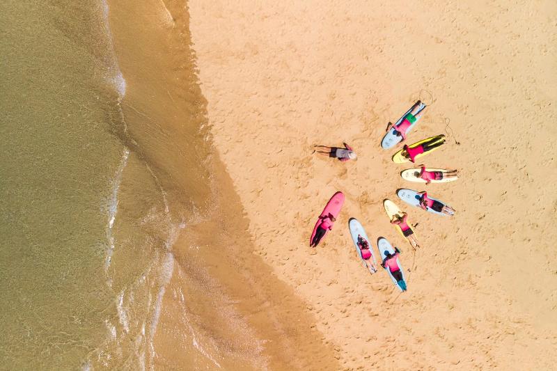Teilnehmer liegen auf Surfbrettern am Strand auf der Surffreizeit