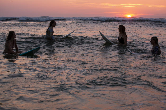 Mädchen auf Surfbrettern im Sonnenuntergang auf der Surffreizeit
