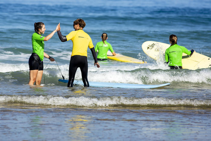 Trainer gibt einem Mädchen High Five auf der Surffreizeit