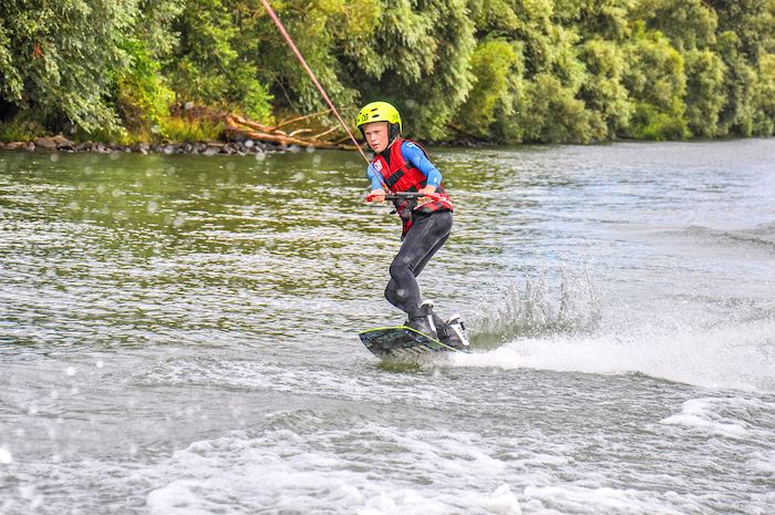 Teilnehmer bei einem Kitesurf-Camp surft auf einem Fluss