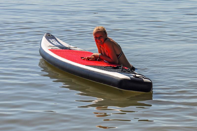 Mädchen ruht sich im Feriencamp Niederland auf ihrem Stand-up-paddle Board aus