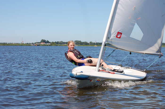 Ein Mädchen segelt alleine auf einem kleinen Segelschiff im Segelcamp für Kinder