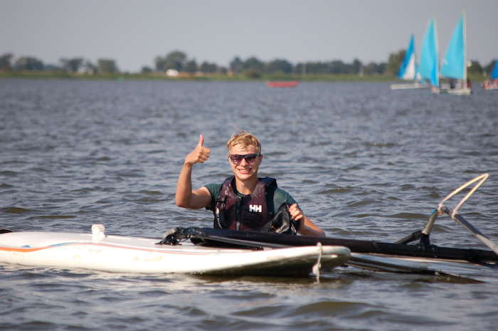 Ein Junge der Sprachreise Niederlande zeigt einen Daumen nach oben im Wasser beim Windsurfen