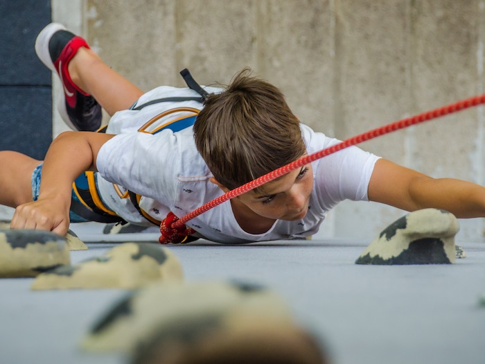 Junge klettert an Kletterwand im Action Camp