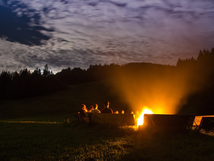 Teilnehmer einer Jugendfreizeit sitzen am Lagerfeuer
