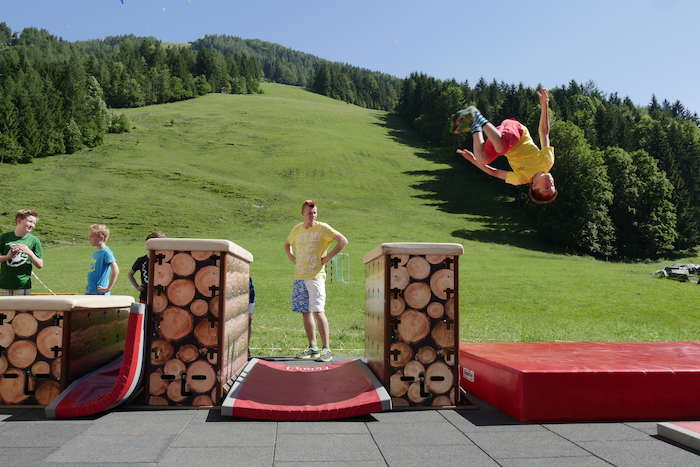 Junge macht Salto bei Parcours im Ferienlager am See