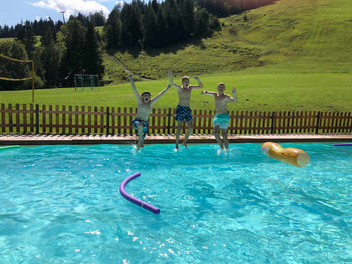 3 Kinder springen in Tirol vom Beckenrand in den Pool