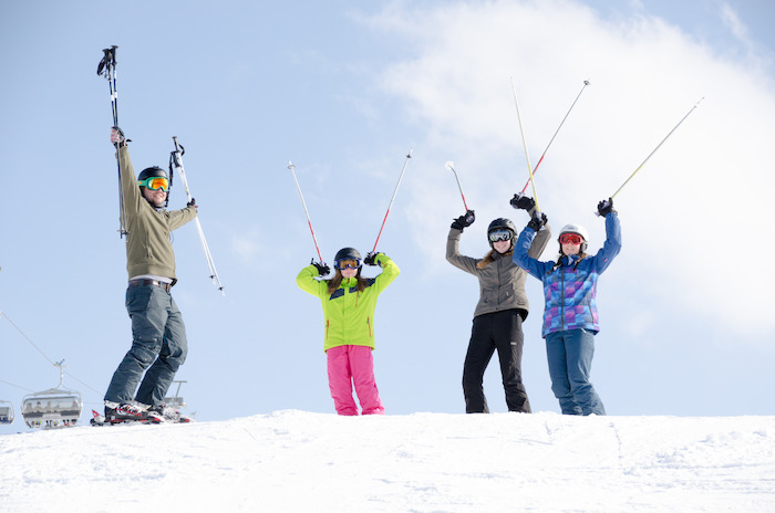 Teilnehmer einer Skifreizeit heben Skistöcker in die Luft