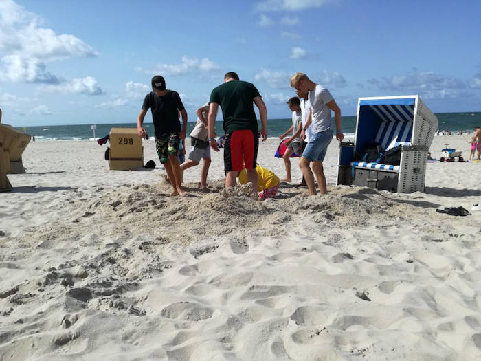 Jugendliche beim Sandbuddeln am Strand im Sommercamp auf Sylt