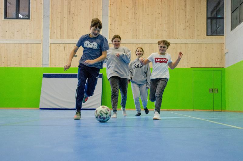 Vier Teilnehmer einer Skifreizeit spielen zusammen Indoorfussball