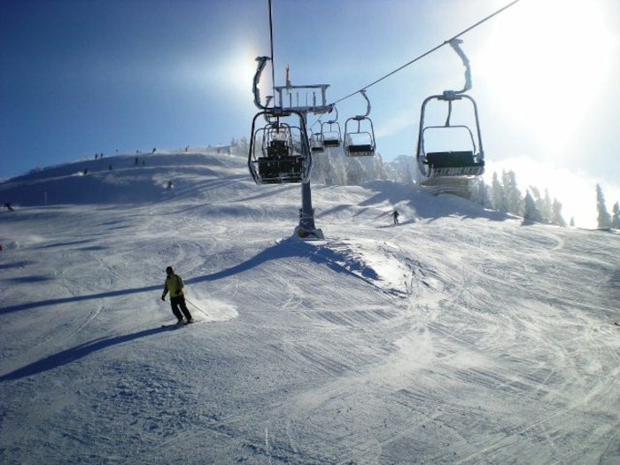 Ein Jugendlicher beim Skifahren Semesterferien auf der Piste mit Sessellift im Hintergrund