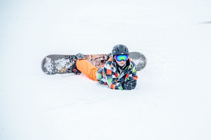 Ein Junge eines Snowboard-camps fährt Snowboard.