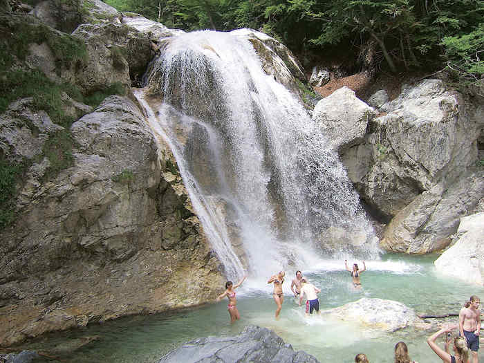 Die Teilnehmer des Feriencamps Kroatien baden in einem Gewässer mit Wasserfall