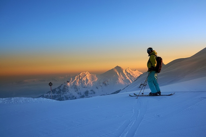 Ein Kind steht am Ski-Abhang eines Berges in den Alpen im Ferienlager Kinder