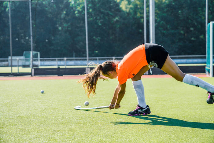 Mädchen schlägt auf Hockeyball im Sport Feriencamp