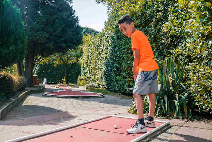 Junge spielt Minigolf im Sport Feriencamp