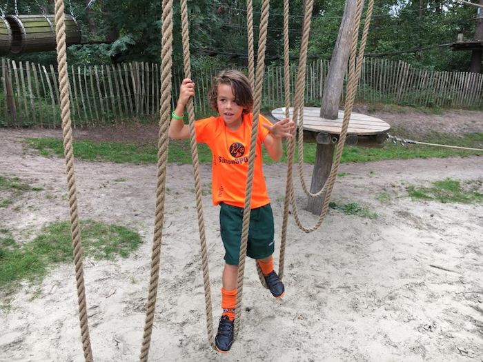 Junge klettert auf Spielplatz im Sport Feriencamp
