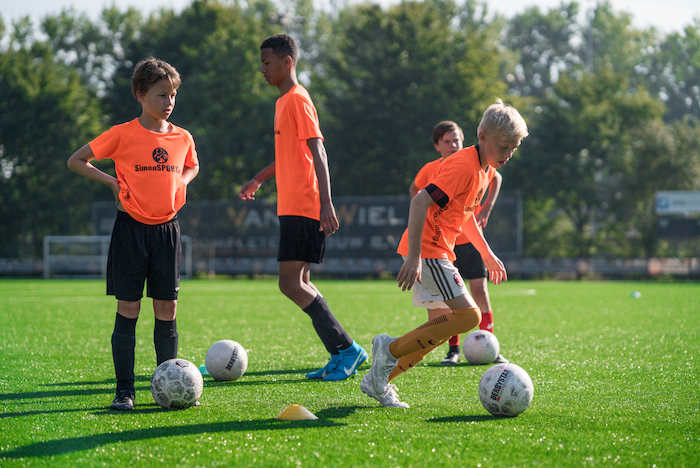 Teilnehmer des Sommercamp Holland spielen auf einem Kunstrasenplatz Fußball