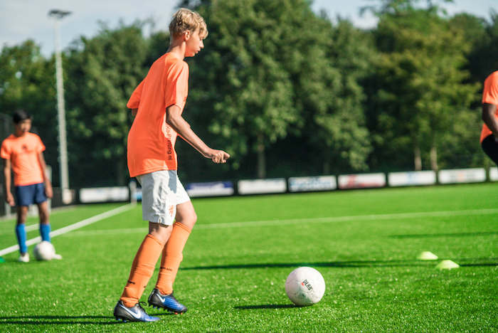Junge schiesst auf Ball im Sport Feriencamp