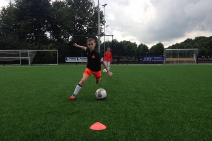 Junge schiesst Fussball im Sport Feriencamp