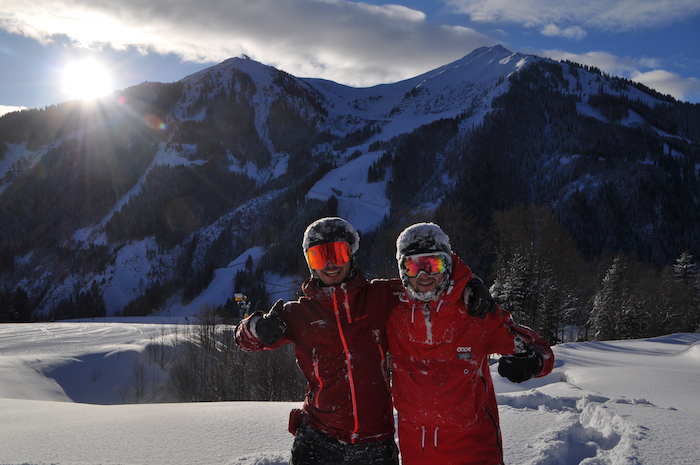 Zwei Jugendliche stehen in Winterkleidung an einem Skihang