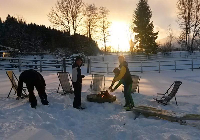 Lagerfeuer mit Sonnenuntergang im Schnee im Skilager