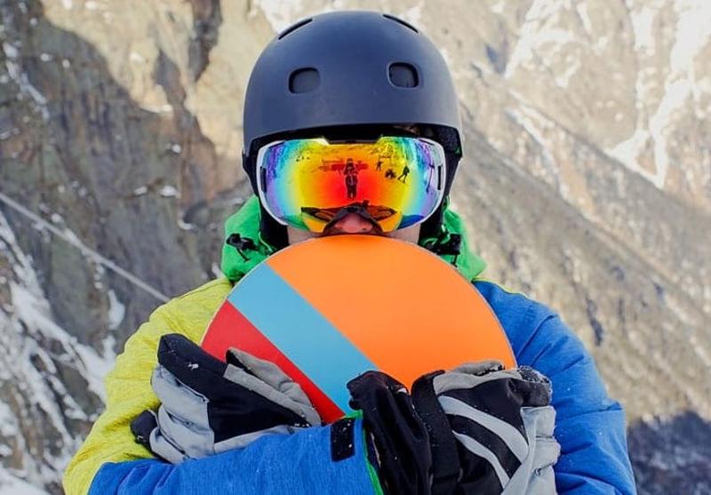 Junge hält Snowboard im Skilager