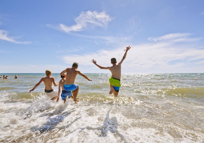 Vier Jungs springen ins Meer im Jugendcamp