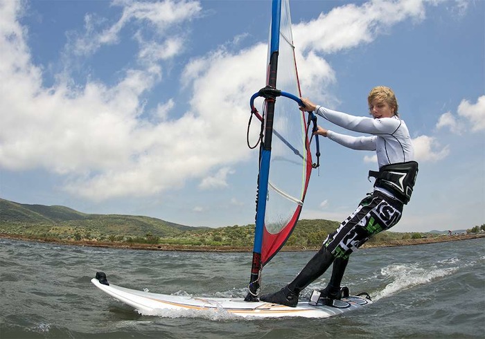Junge steht auf dem Windsurfbrett im Jugendcamp