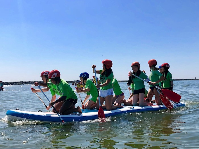 Teilnehmer eines Sprach-Camps fahren zusammen Boot
