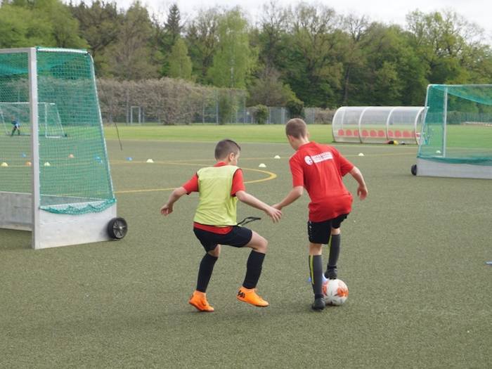 Zwei Kinder spielen auf einem Kunstrasenplatz gegeneinander Fußball