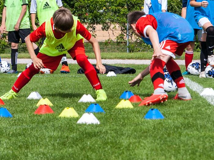 Zwei Jungen trainieren Fußball und laufen von Hütchen zu Hütchen